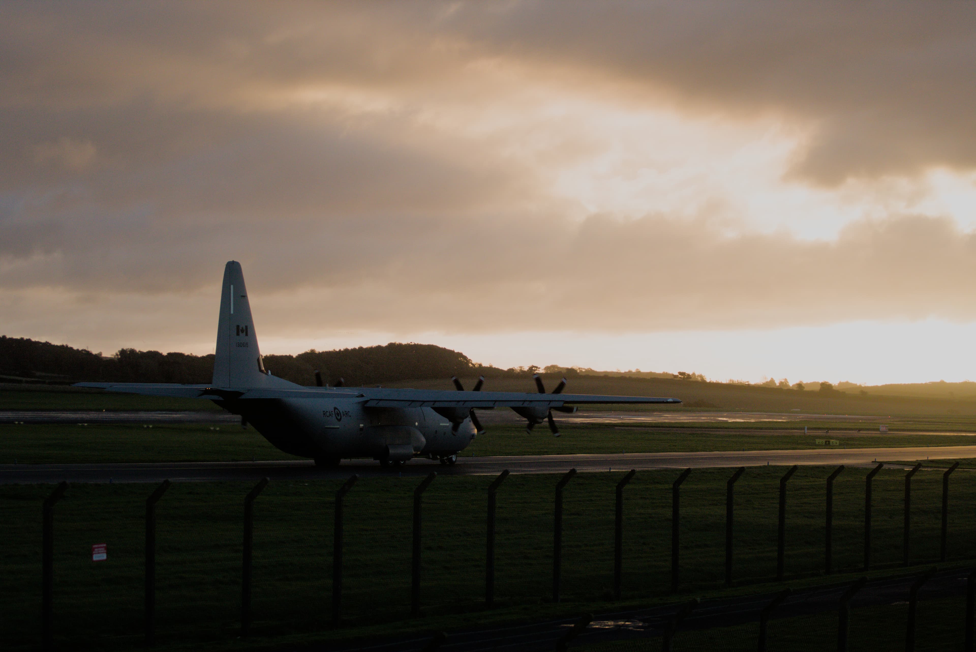 Royal Canadian Air Force Hercules silhouetted against a dramatic sunset at Glasgow Prestwick Airport